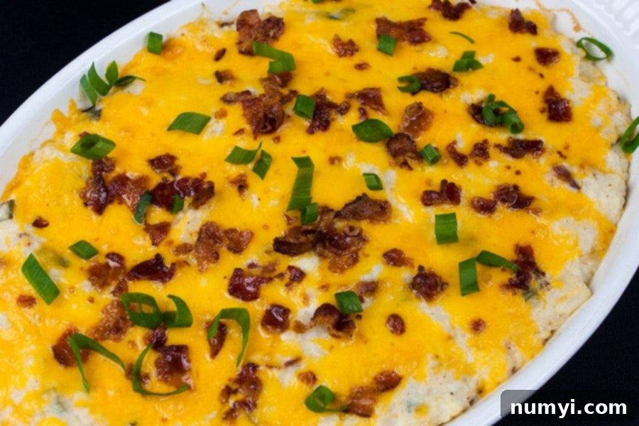 Baked Loaded Cauliflower Mash Casserole in a white ceramic dish, hot and bubbly from the oven.