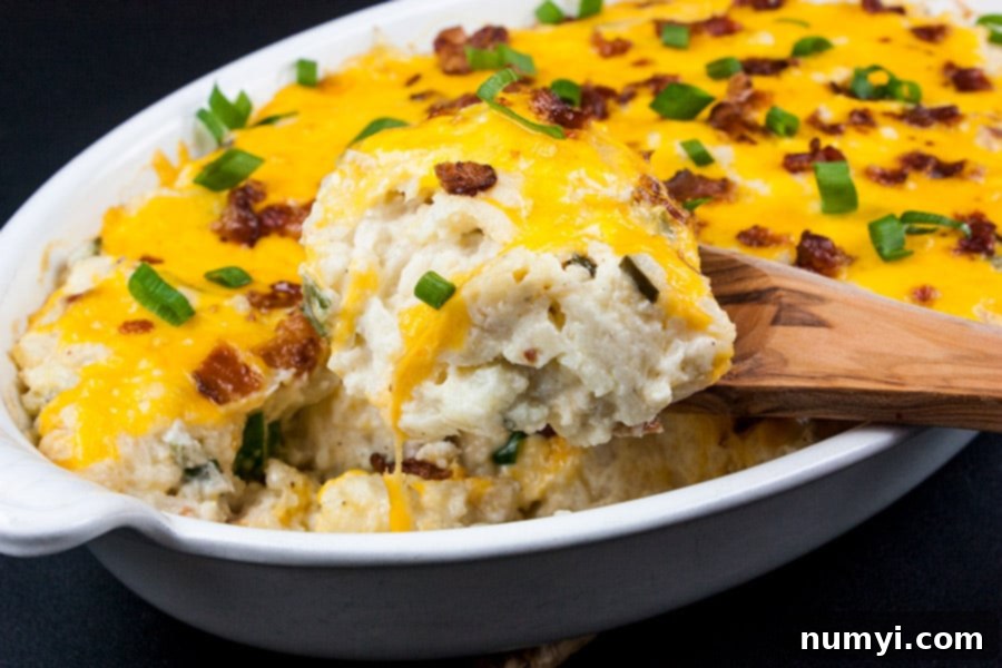 Loaded Cauliflower Mash Casserole – a serving scooped out with a wooden spoon, revealing its creamy interior.