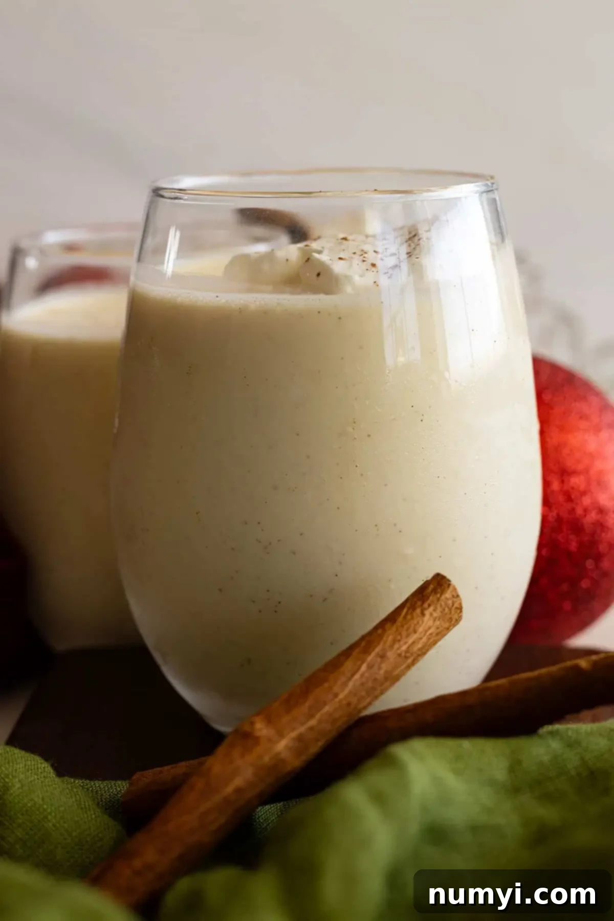 Creamy Homemade Eggnog 6 A glass of eggnog topped with whipped cream.