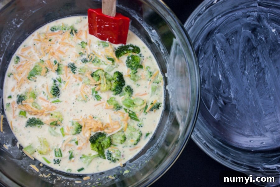 A glass bowl filled with the colorful, mixed ingredients for crustless broccoli cheddar quiche, placed next to a buttered pie plate, ready for baking.