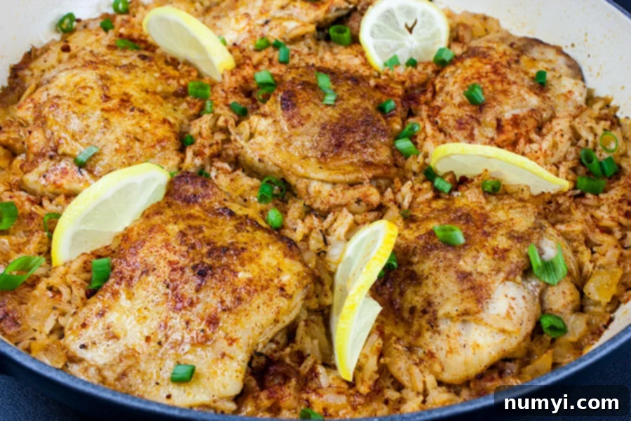 One Pan Spanish Chicken and Rice garnished with lemon slices and chopped green onions.