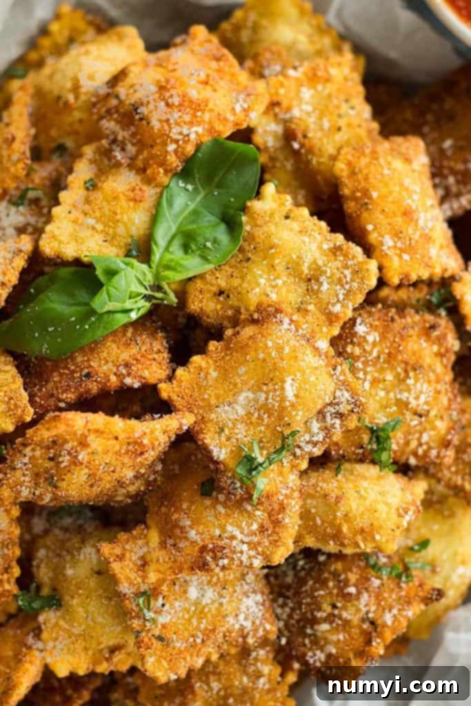 Ultimate Crispy Toasted Ravioli 2 Platter filled with golden brown toasted ravioli, garnished with fresh herbs and served with marinara sauce.
