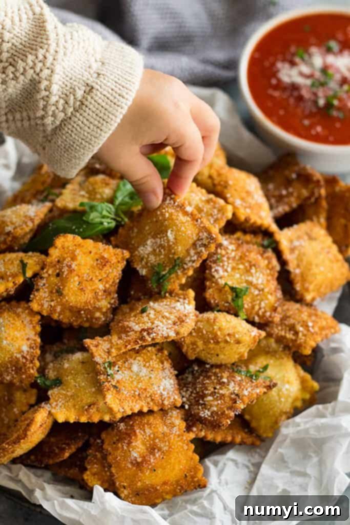 Ultimate Crispy Toasted Ravioli 3 Hand holding a single piece of perfectly toasted ravioli, showing the golden-brown breading and a hint of cheese.