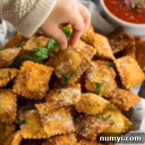 Ultimate Crispy Toasted Ravioli 5 Toasted ravioli sprinkled with parmesan cheese and chopped basil. A child's hand is taking one to eat.