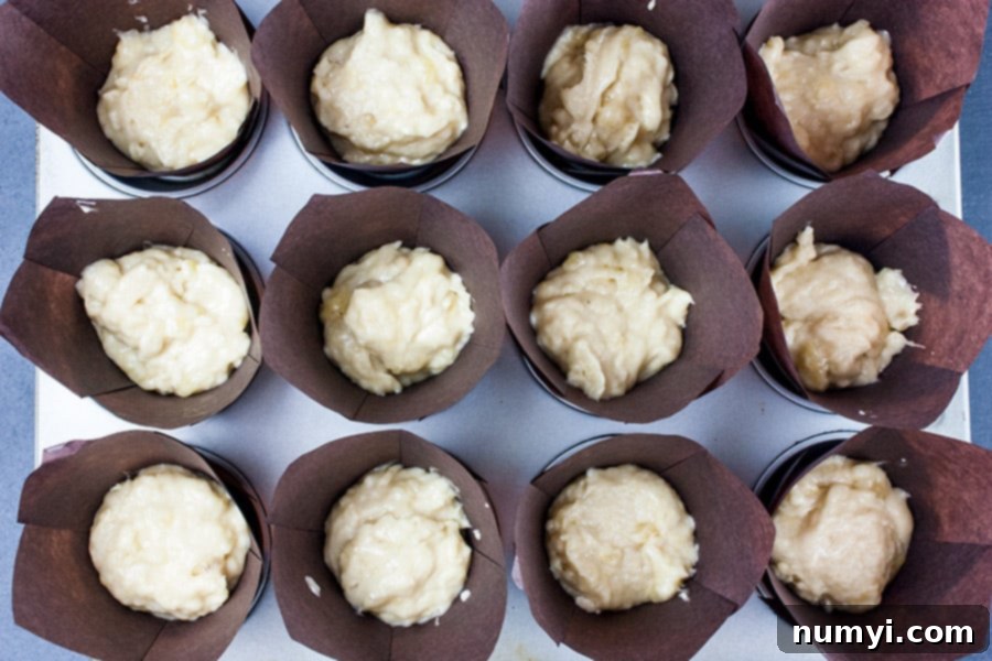 Muffin liners filled with rich banana muffin batter, ready for baking.
