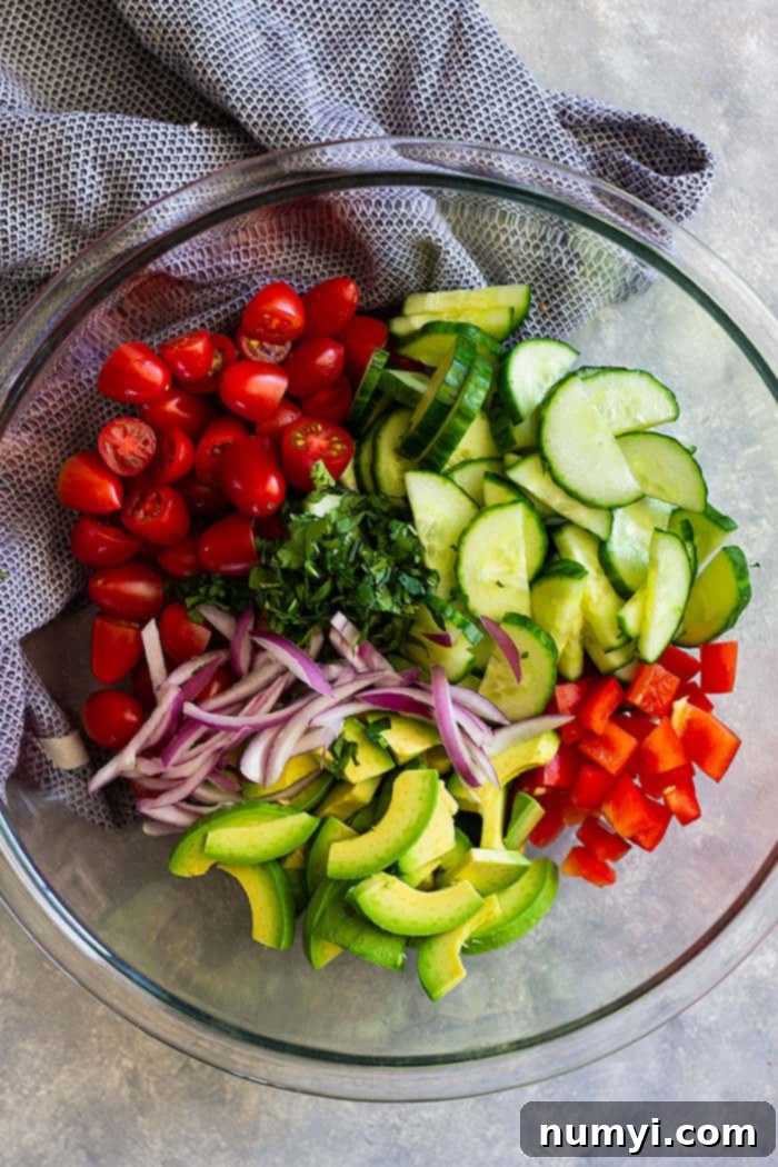 An overhead shot of the simple and refreshing Tomato Cucumber Avocado Salad in a white bowl, ready to be served, highlighting its appealing presentation.