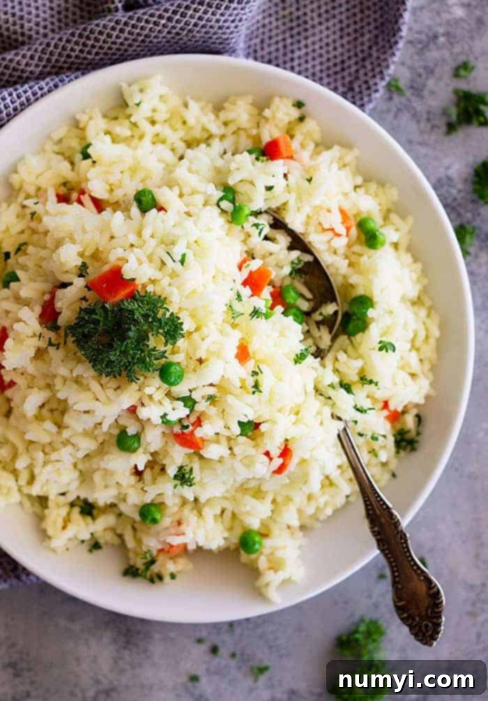 A serving of fluffy rice pilaf with carrots and peas on a plate, ready to be enjoyed with a fork.