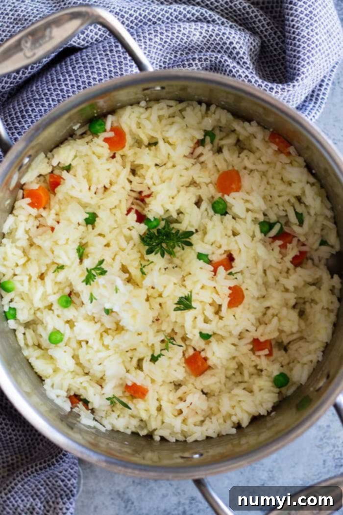 An overhead shot of homemade rice pilaf with carrots and peas, still in the cooking pan after fluffing.
