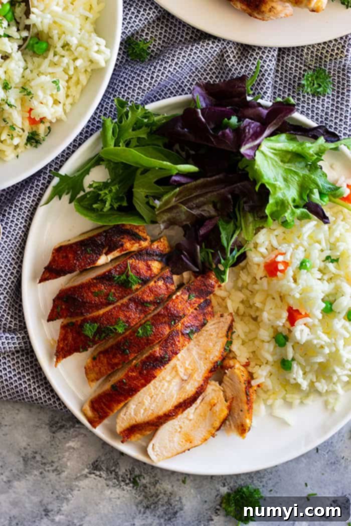 A plate featuring a main course of chicken served alongside a generous portion of vegetable rice pilaf.