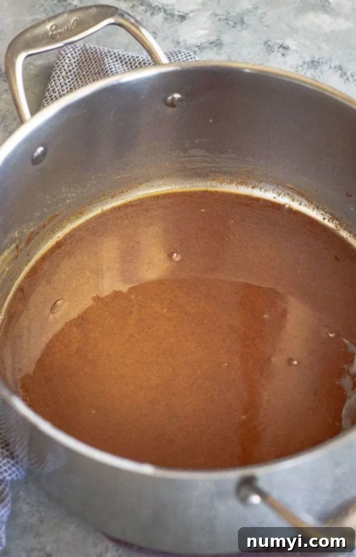 A medium brown roux cooking in a cast iron pan, showing the rich, nutty color essential for a flavorful gumbo base.
