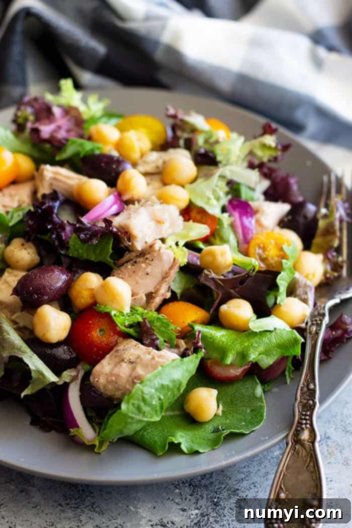 A vibrant Quick Tuscan Tuna Salad in a bowl, featuring tuna, chickpeas, cherry tomatoes, olives, red onion, and fresh greens, drizzled with a light vinaigrette. Perfect for a healthy, no-mayo lunch or dinner.
