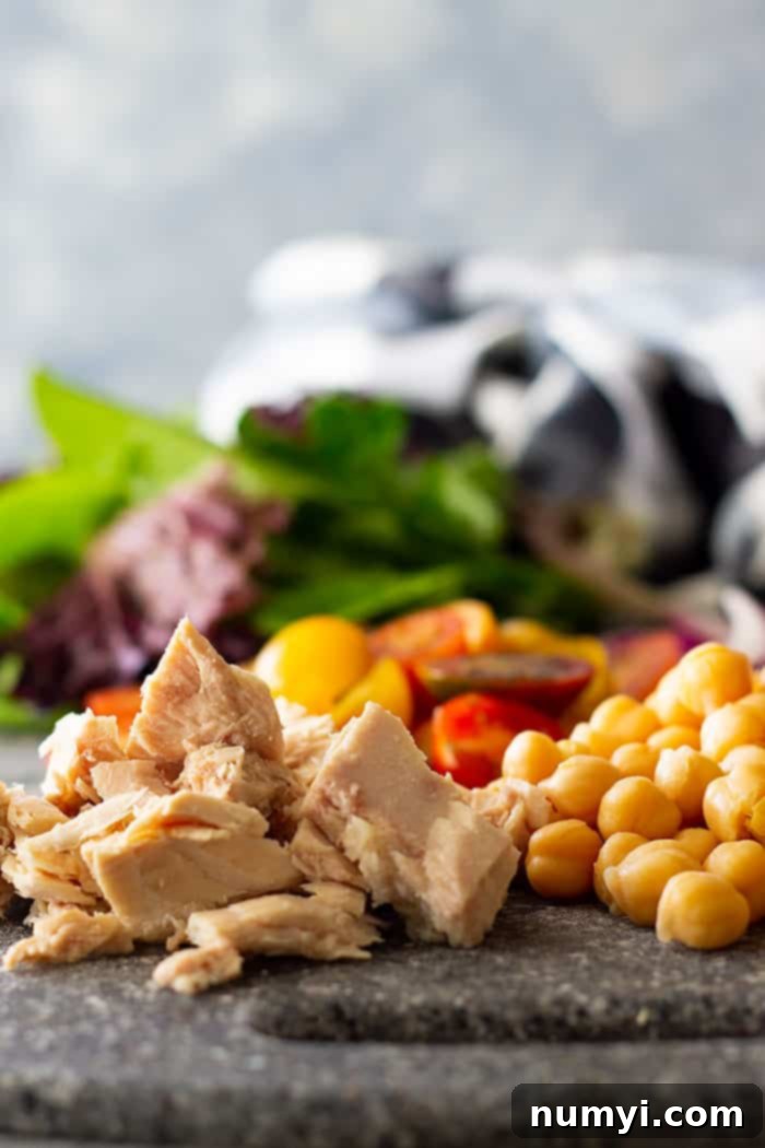 A selection of Quick Tuscan Tuna Salads prepared in mason jars, showcasing the colorful layers of dressing, chickpeas, tuna, vegetables, and greens – ideal for healthy, grab-and-go meal prep.