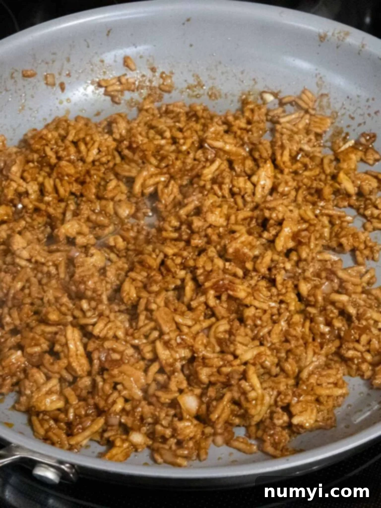 The ground chicken mixture, now richly coated with a vibrant blend of Asian spices and savory sauces, simmering gently in a skillet to combine flavors.