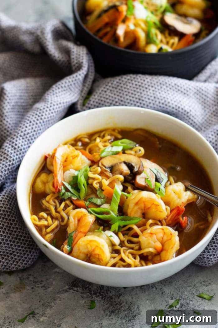 white bowl of shrimp ramen garnished with green onions and a slice of lime