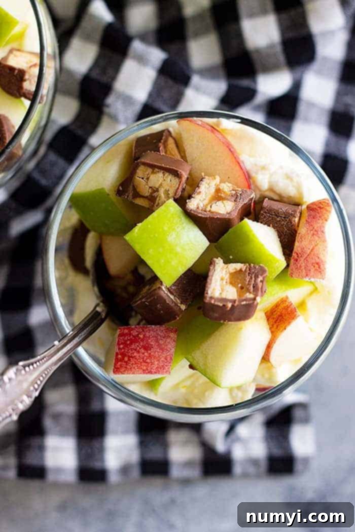 Top view of Snicker apple salad in a small glass bowl with a spoon.