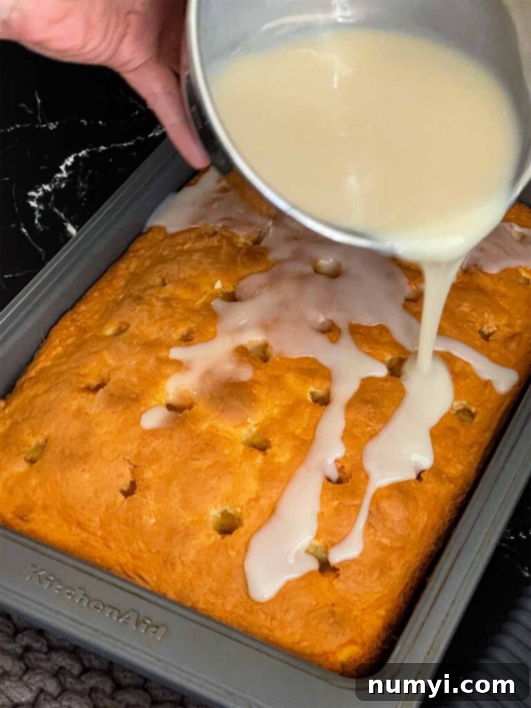 The rich cream of coconut mixture being carefully poured over the still-hot coconut sheet cake in its baking pan.