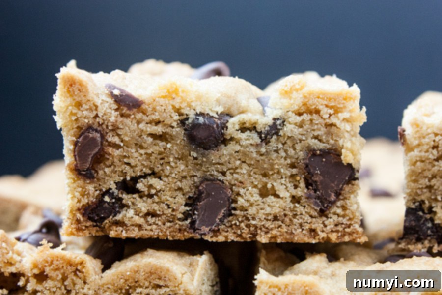 Close-up of a single chocolate chip cookie bar, showing its gooey center and abundant chocolate chips.