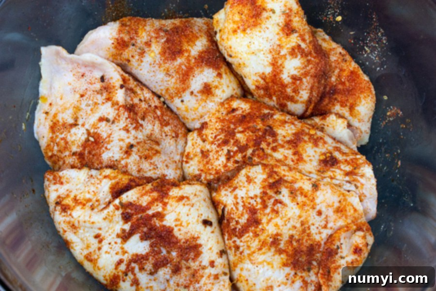 One Pan Chicken and Dirty Rice - chicken thighs covered in marinade in a glass bowl, ready for cooking.