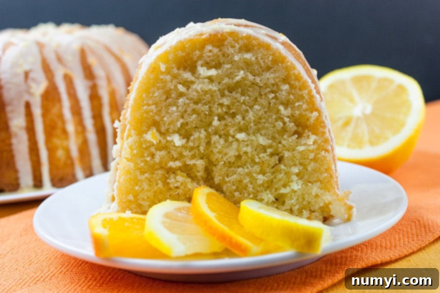 Lemon-Orange Pound Cake on a white plate, beautifully drizzled with glaze and garnished with citrus slices.