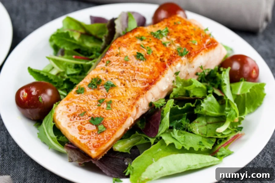 Pan-Seared Salmon Salad with Lemon Dijon Vinaigrette on a white plate, showcasing the perfectly cooked salmon and fresh greens.