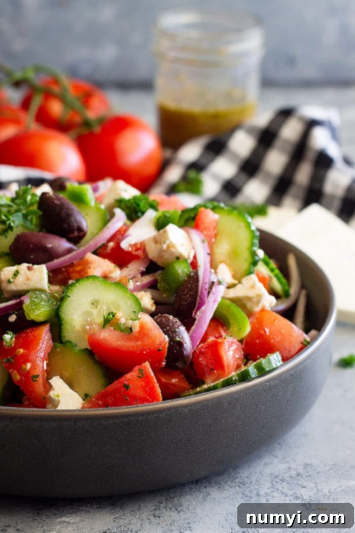 Close up view of a vibrant Easy Greek Salad in a large serving bowl, showcasing the colorful mix of chopped tomatoes, cucumbers, red onion, green bell pepper, Kalamata olives, and feta cheese.
