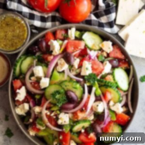 Close up shot of a colorful Easy Greek Salad with juicy tomatoes, crisp cucumbers, green bell peppers, red onion, black Kalamata olives, and creamy feta cheese. Ideal for a healthy meal.
