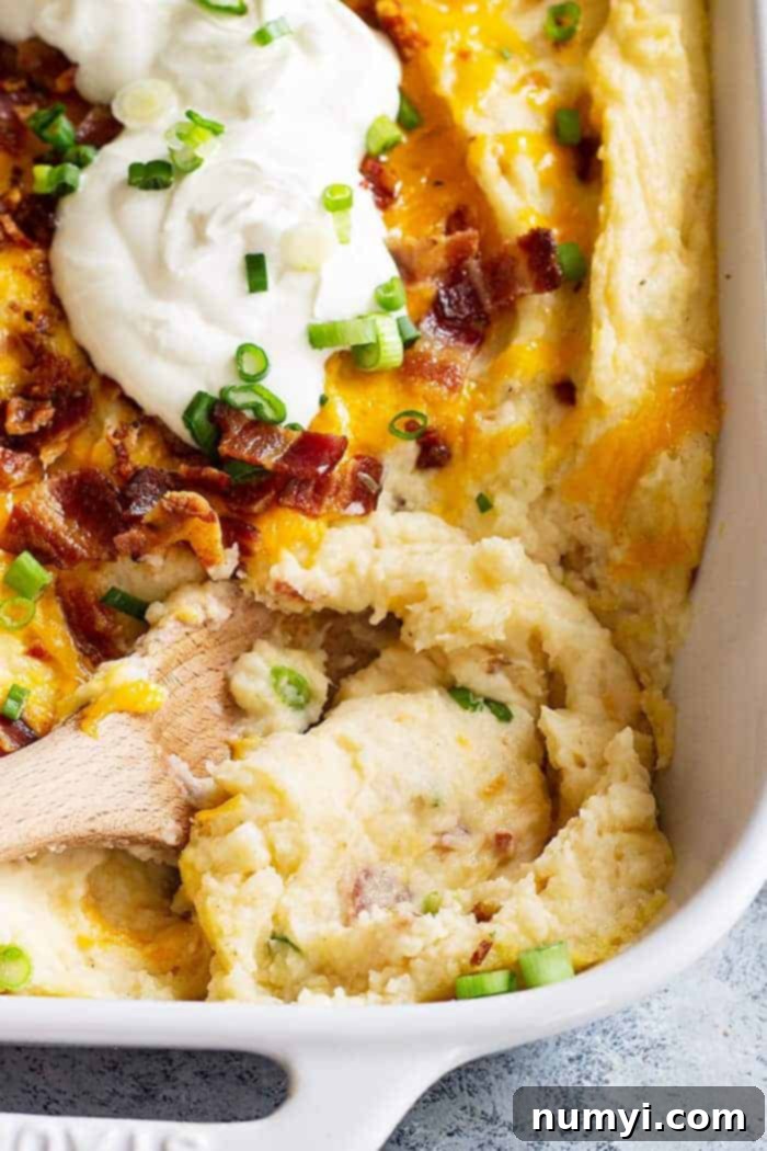 closeup: serving a helping of cheesy mashed potato casserole from the baking dish