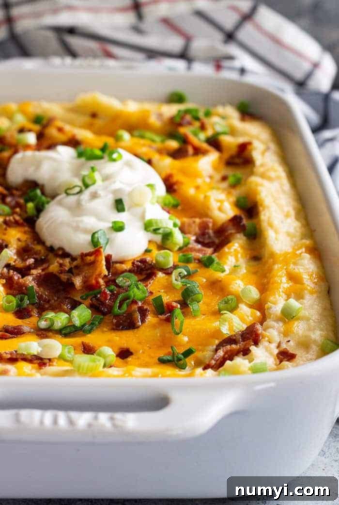 closeup: white baking dish full of mashed potato loaded casserole, with green onions and bacon on top