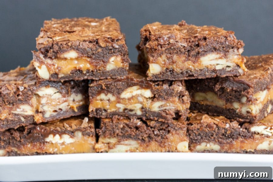 Decadent Turtle Brownies 7 Individually cut ultimate turtle brownies, showcasing their irresistible layers of chocolate, caramel, and pecans, arranged on a crisp white plate.