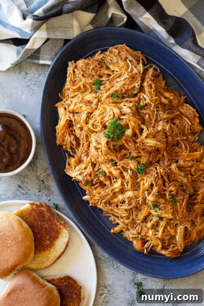 A large plate of slow cooker bbq chicken, garnished with fresh herbs.