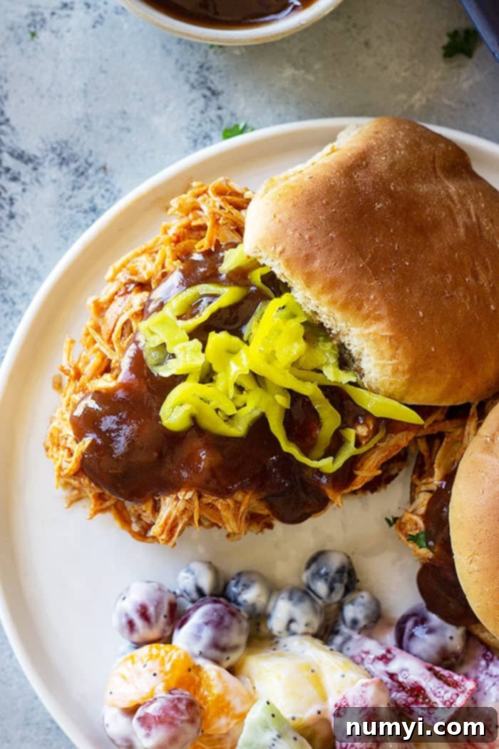 Close up picture of slow cooker bbq chicken on a bun with bbq sauce, ready to serve.