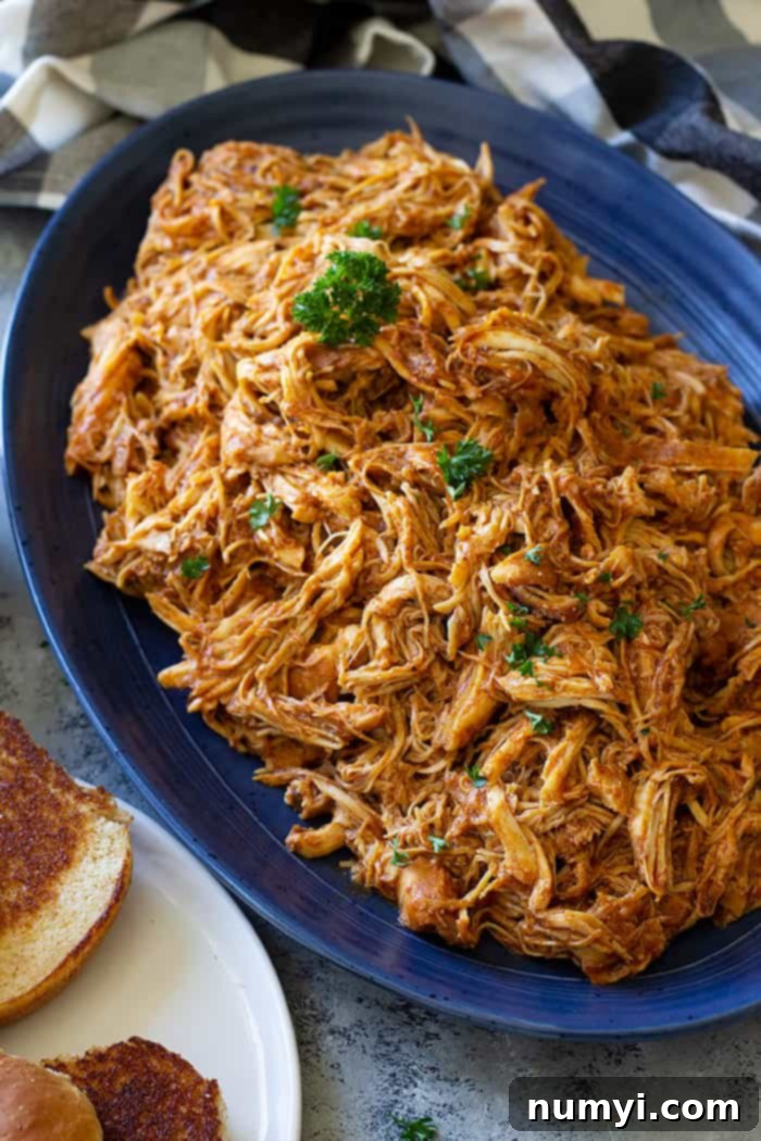 A large serving platter filled with shredded slow cooker bbq chicken.