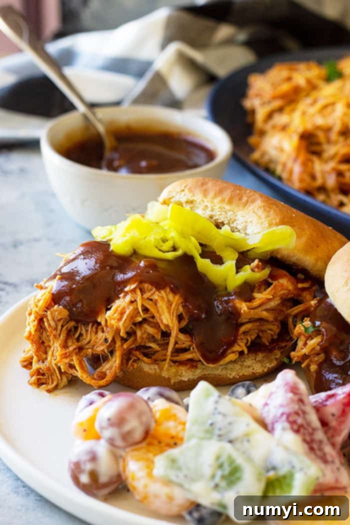 Close up picture of slow cooker bbq chicken on a bun with bbq sauce, showcasing the shredded texture.