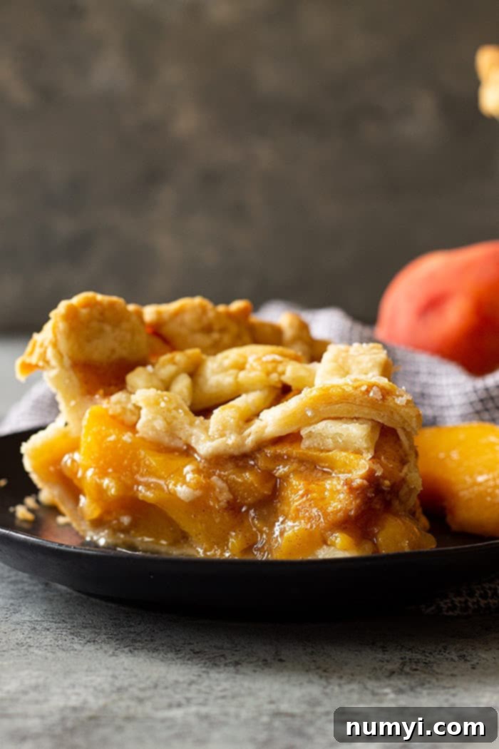 A slice of peach pie with an all butter crust.