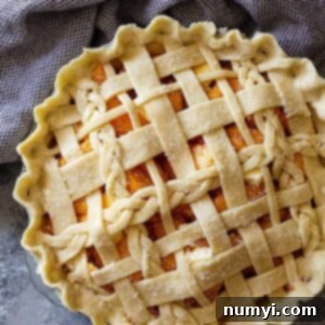 Top down view of a peach pie with an all butter crust lattice top.