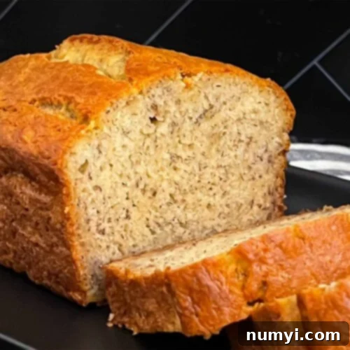 Melt-In-Your-Mouth Banana Bread Made Simple 9 Slices of banana bread and the remaining loaf on a dark plate on a dark surface.