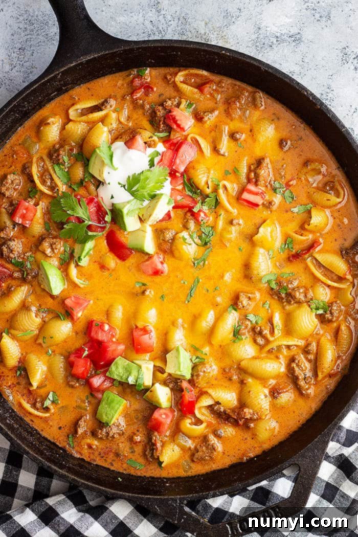 Creamy Cheesy Taco Pasta 2 Top down picture of taco pasta in a large skillet. Topped with taco toppings.