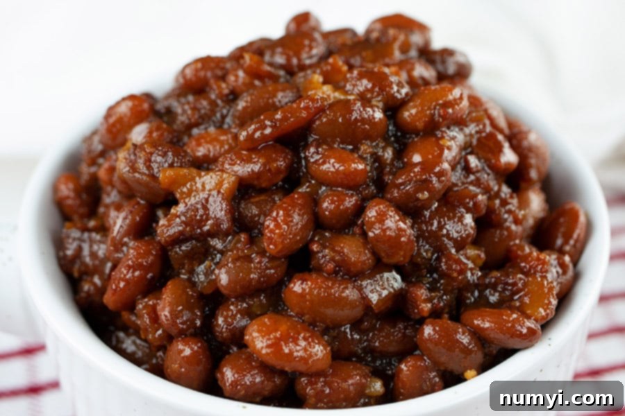A serving of Slow Cooker Boston Baked Beans in a white ramekin, garnished with parsley.