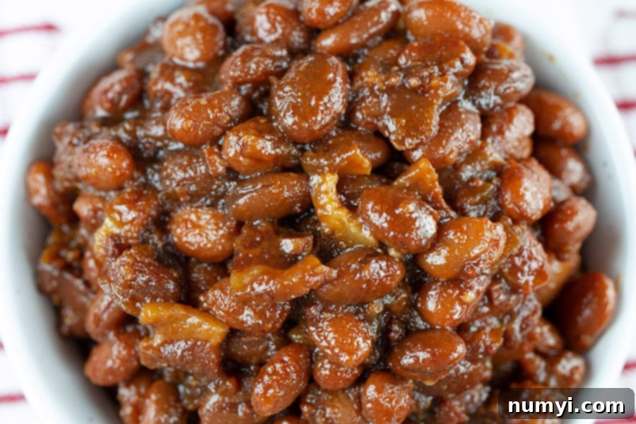 A close-up of Slow Cooker Boston Baked Beans in a light colored serving bowl.