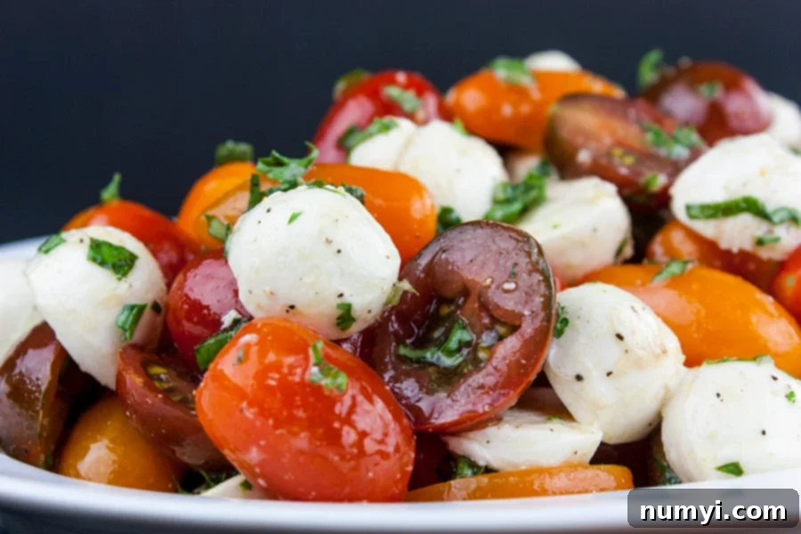 Close up of the tomato mozzarella salad in a white bowl.
