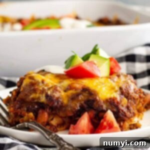 A slice of Mexican Casserole on a white plate with a fork.
