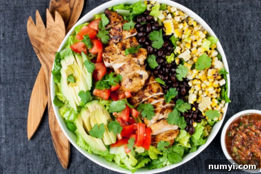 Large white bowl filled with a vibrant Southwest Grilled Chicken Salad featuring sliced grilled chicken, corn, black beans, tomatoes, avocado, and fresh cilantro