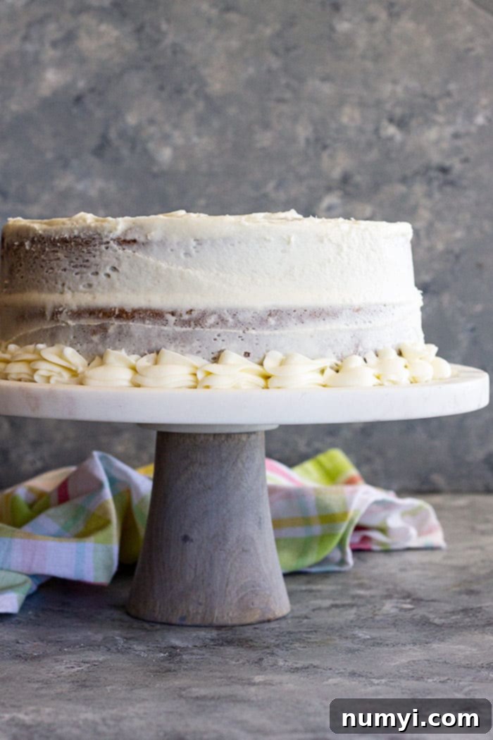 A cake on a stand covered in cream cheese frosting.