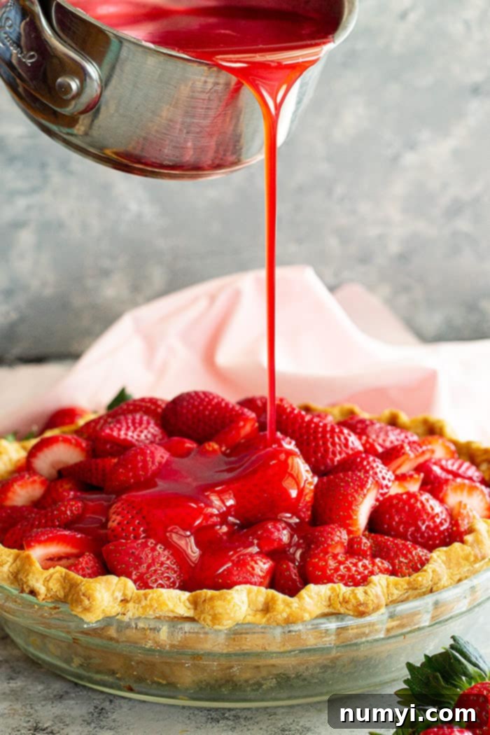 Pouring strawberry jello filling over the pie. 