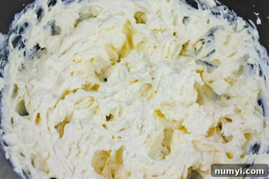 Buffalo Chicken Dip - cream cheese mixture in a mixing bowl being stirred.