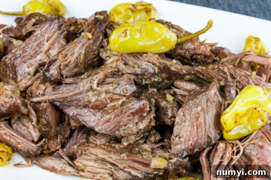Crock Pot Mississippi pot roast on a white platter garnished with pepperoncini.