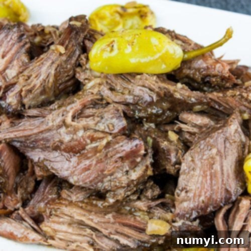 Crock Pot Mississippi pot roast on a white platter garnished with pepperoncini.