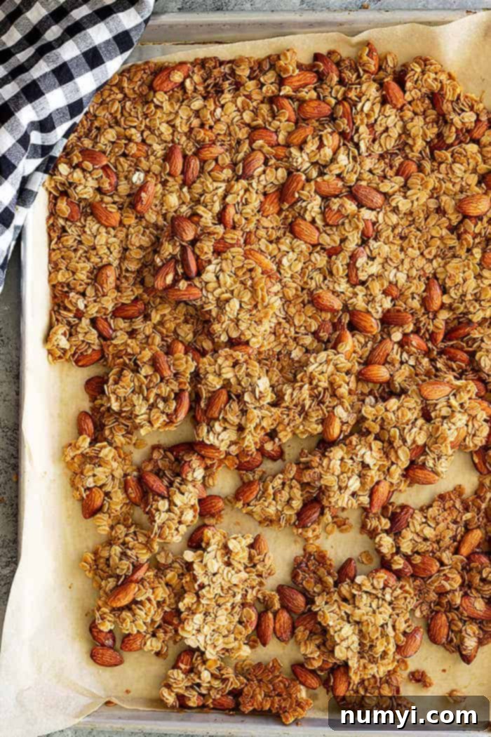 overhead: honey almond granola on a parchment lined baking sheet after baking