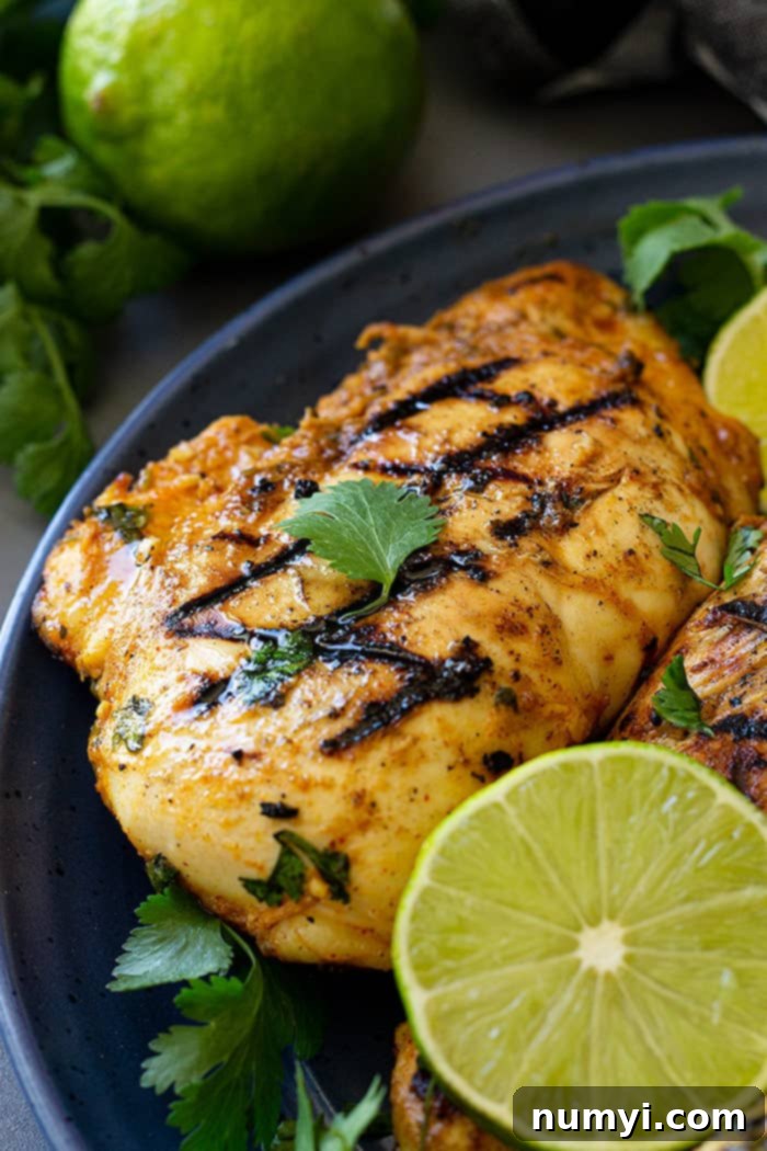 Grilled Cilantro Lime Chicken on a blue plate garnished with fresh lime wedges and cilantro sprigs.