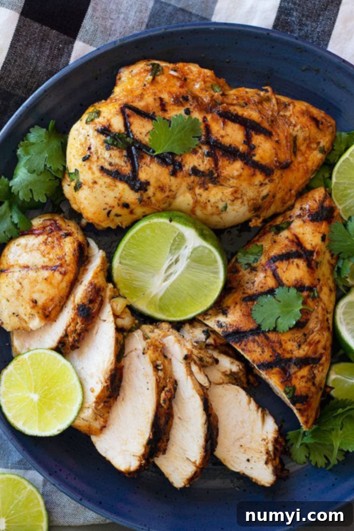 Sliced Cilantro Lime Chicken pieces on a blue plate, garnished with fresh cilantro and lime wedges.